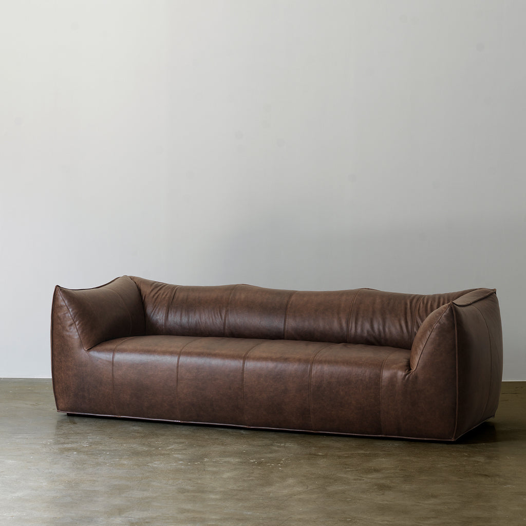 Deep brown curved leather sofa front three-quarter view