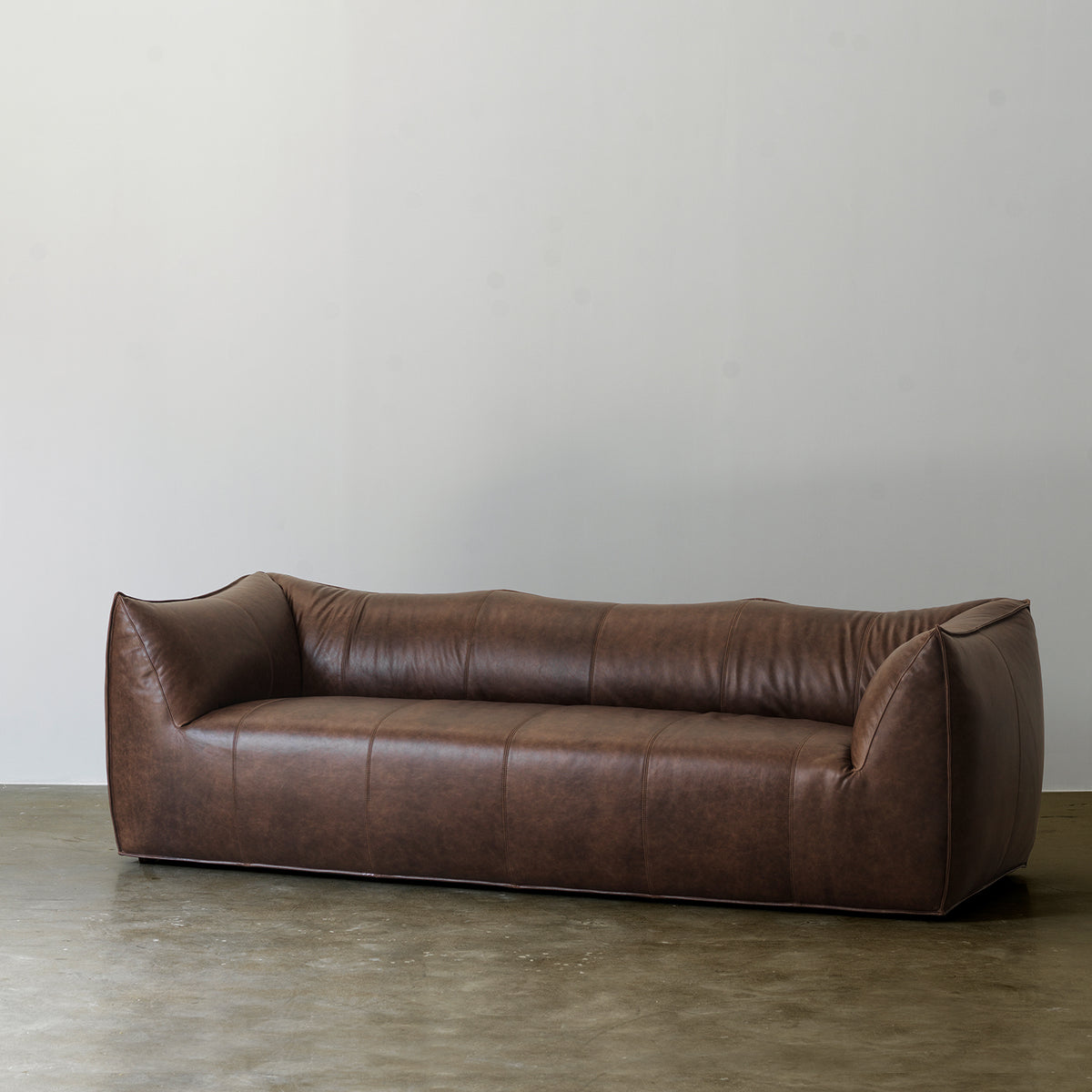 Deep brown curved leather sofa front three-quarter view