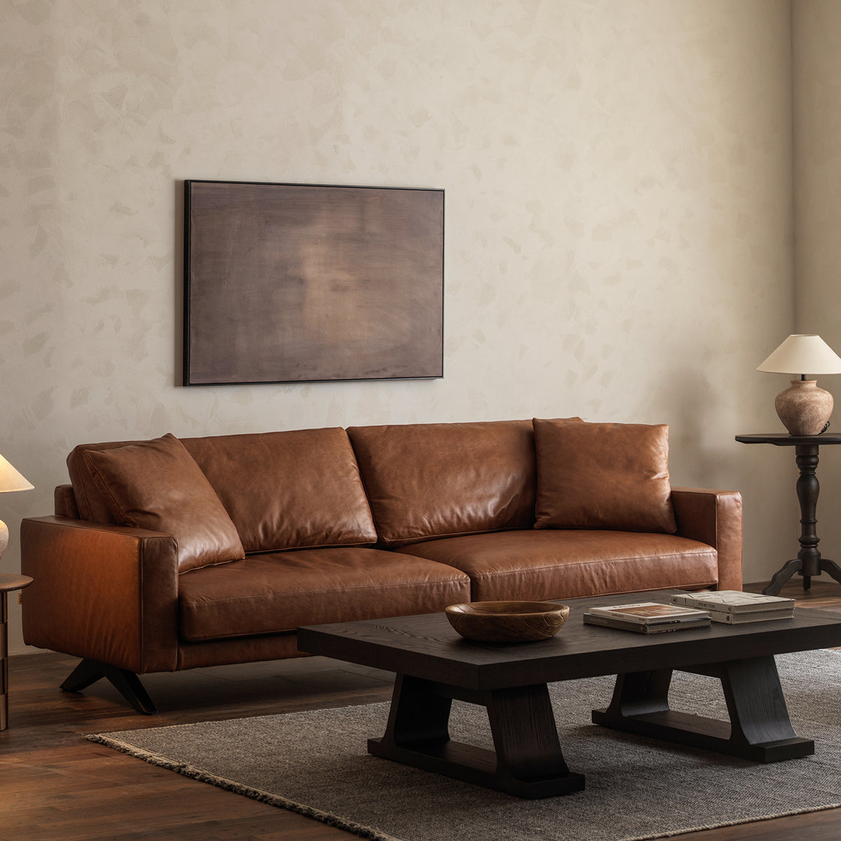 Three-quarter view of vintage leather sofa in a mid-century styled living room with low coffee table