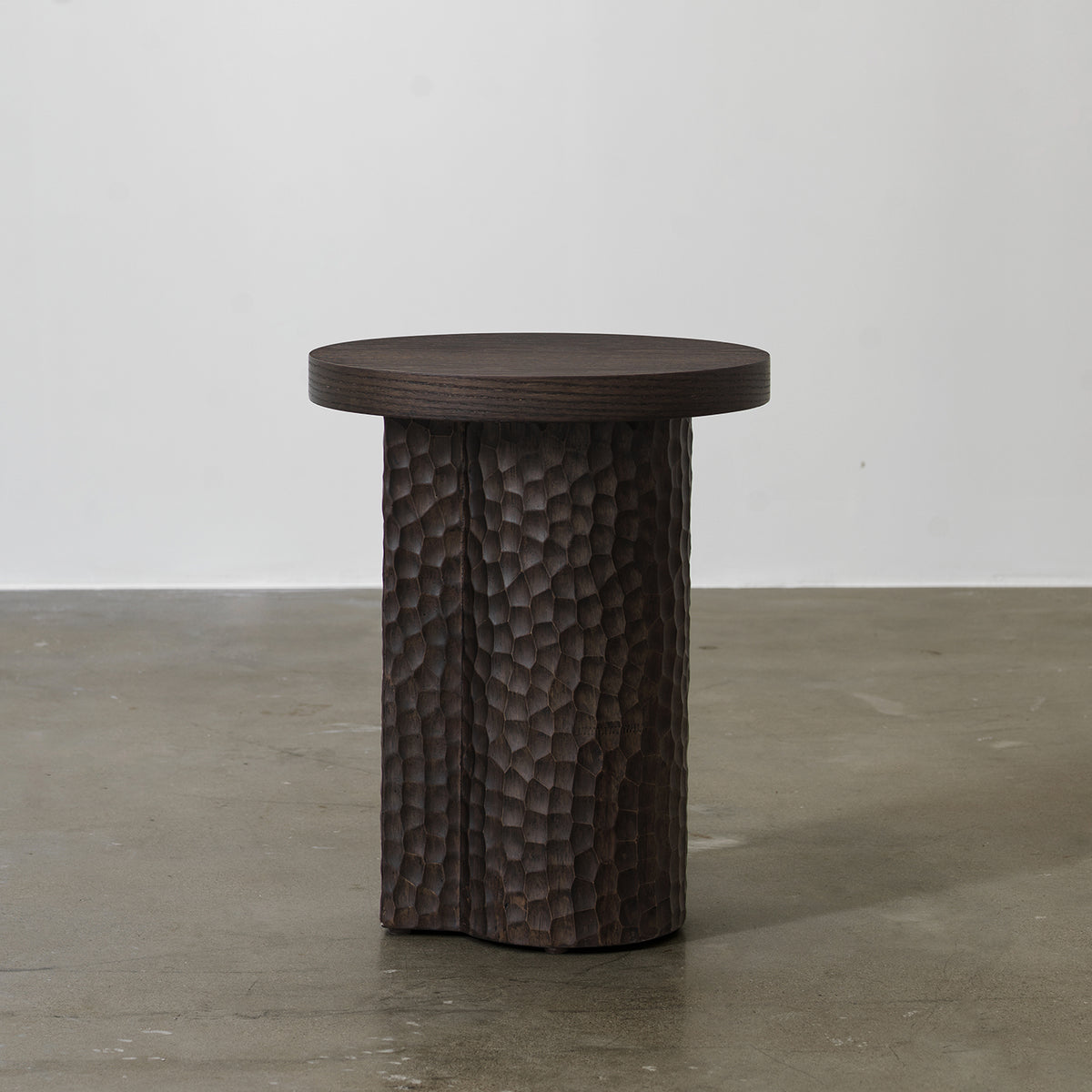Front view of distressed red oak round pedestal side table with hand-chiseled textured base