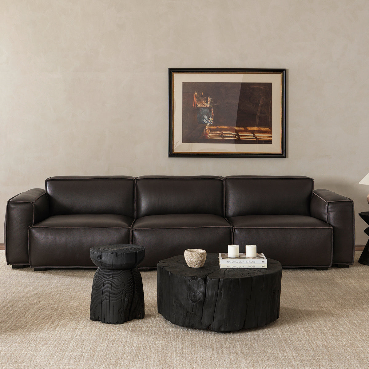 Front view of contemporary low-profile 3-seater black leather sofa styled with dark wood accent furniture