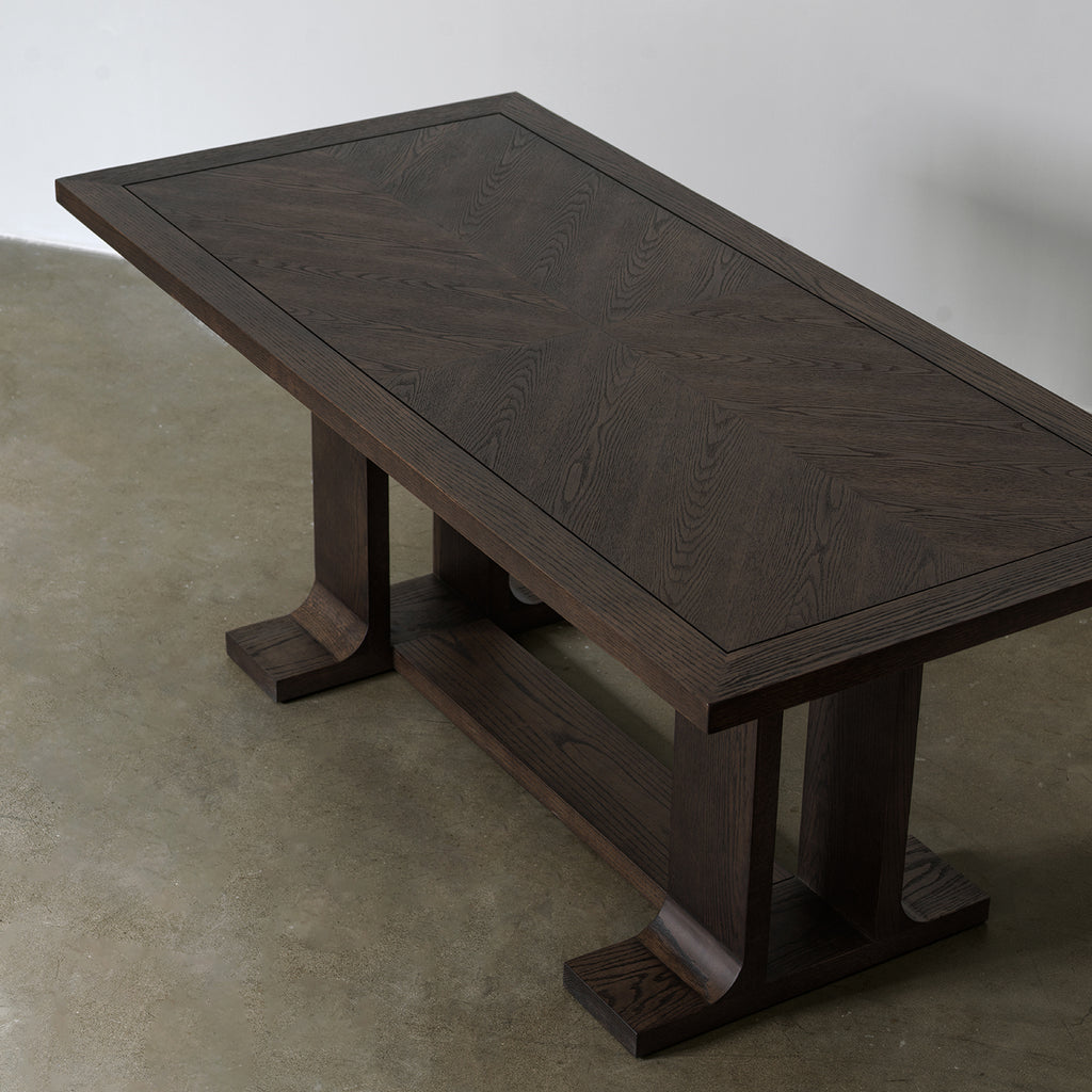 Elevated view of rectangular dining table displaying geometric pattern wood veneer top and solid border frame