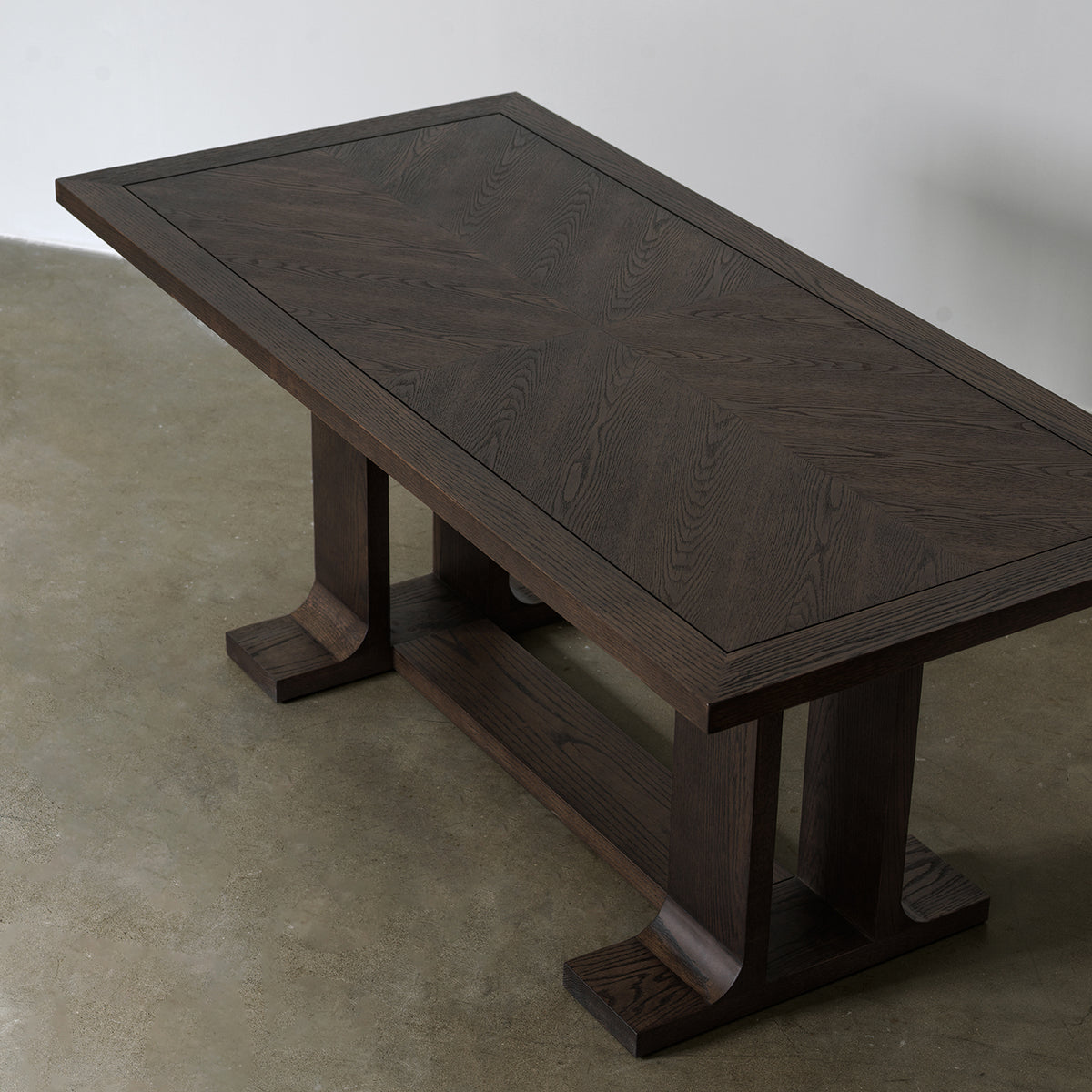 Elevated view of rectangular dining table displaying geometric pattern wood veneer top and solid border frame