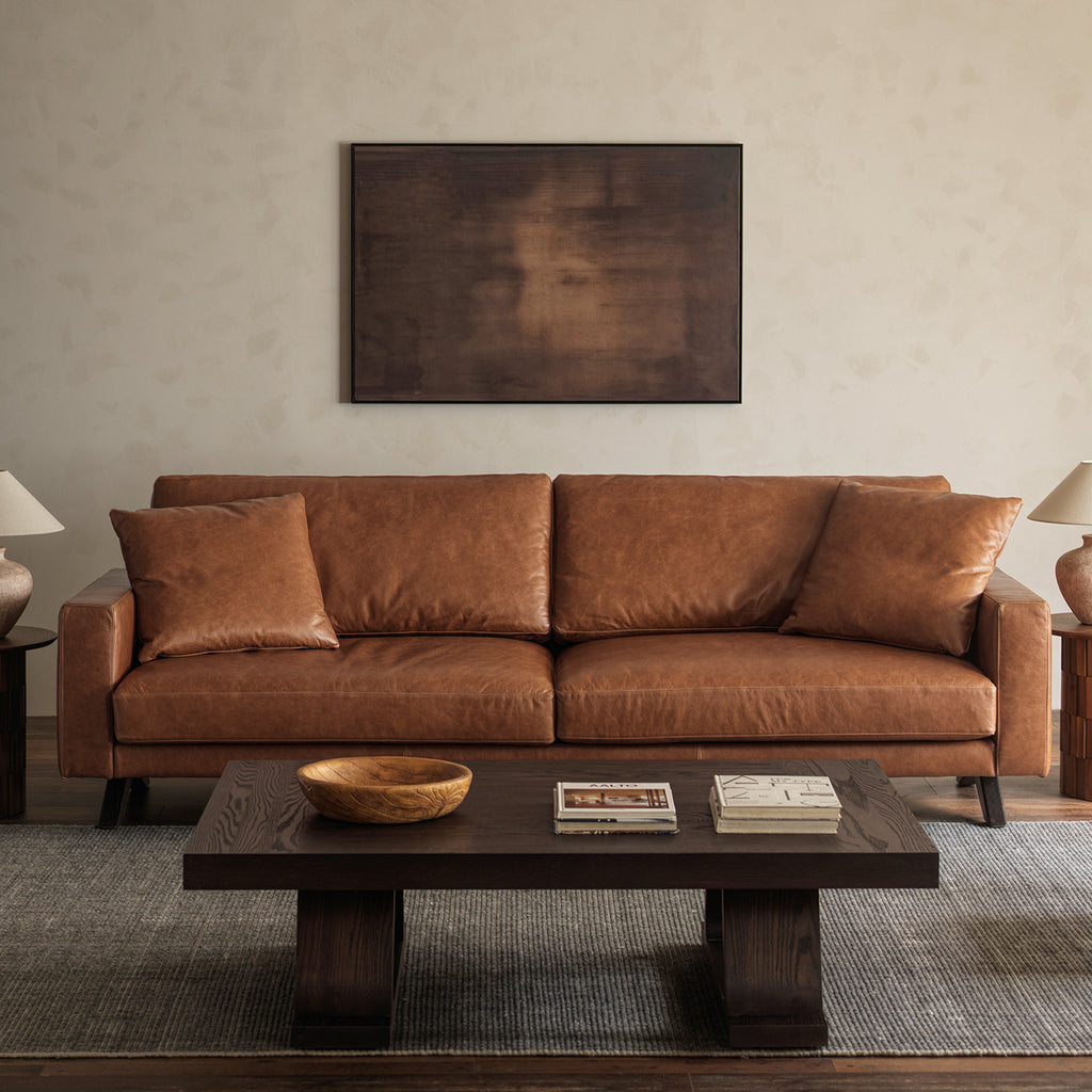 Front view of warm brown leather sofa styled in contemporary vintage interior setting