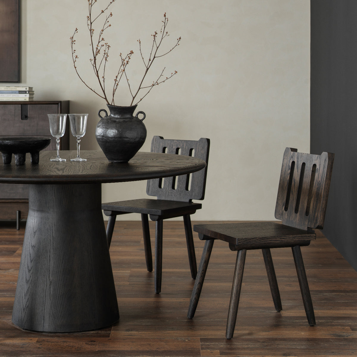 Close-up three-quarter view showing distressed solid wood conical pedestal base and matching chairs