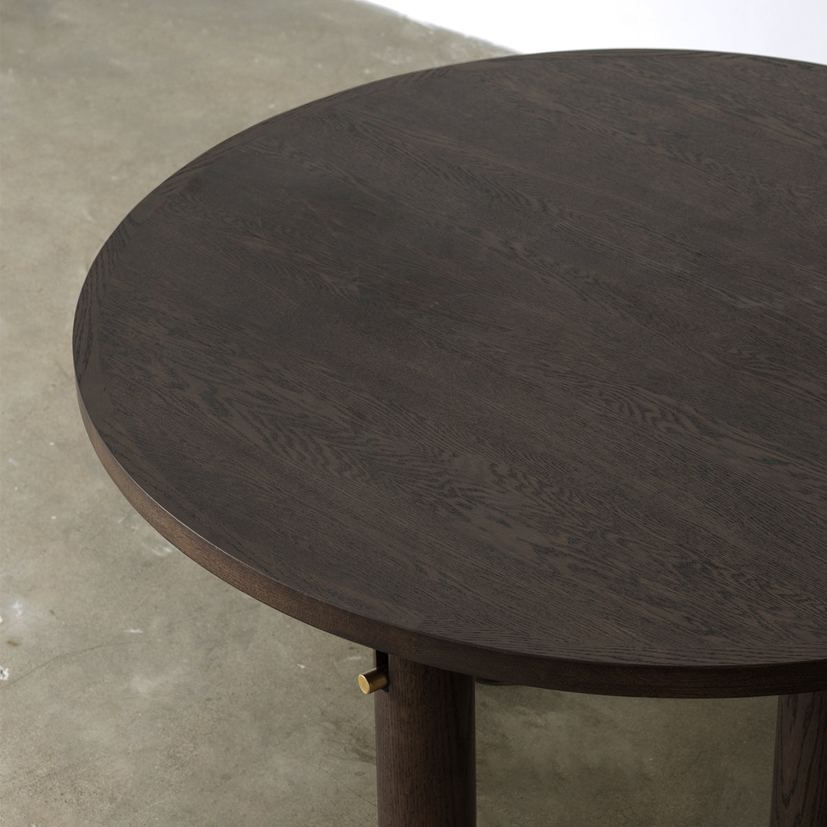 wood grain surface and cylindrical leg with brass accent, angled tabletop detail