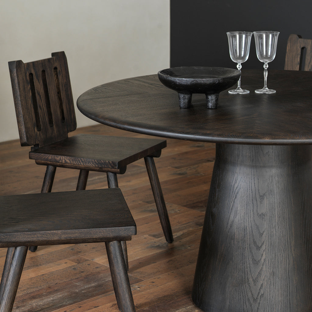 Dining room perspective highlighting distressed round wood tabletop edge and sculptural pedestal base