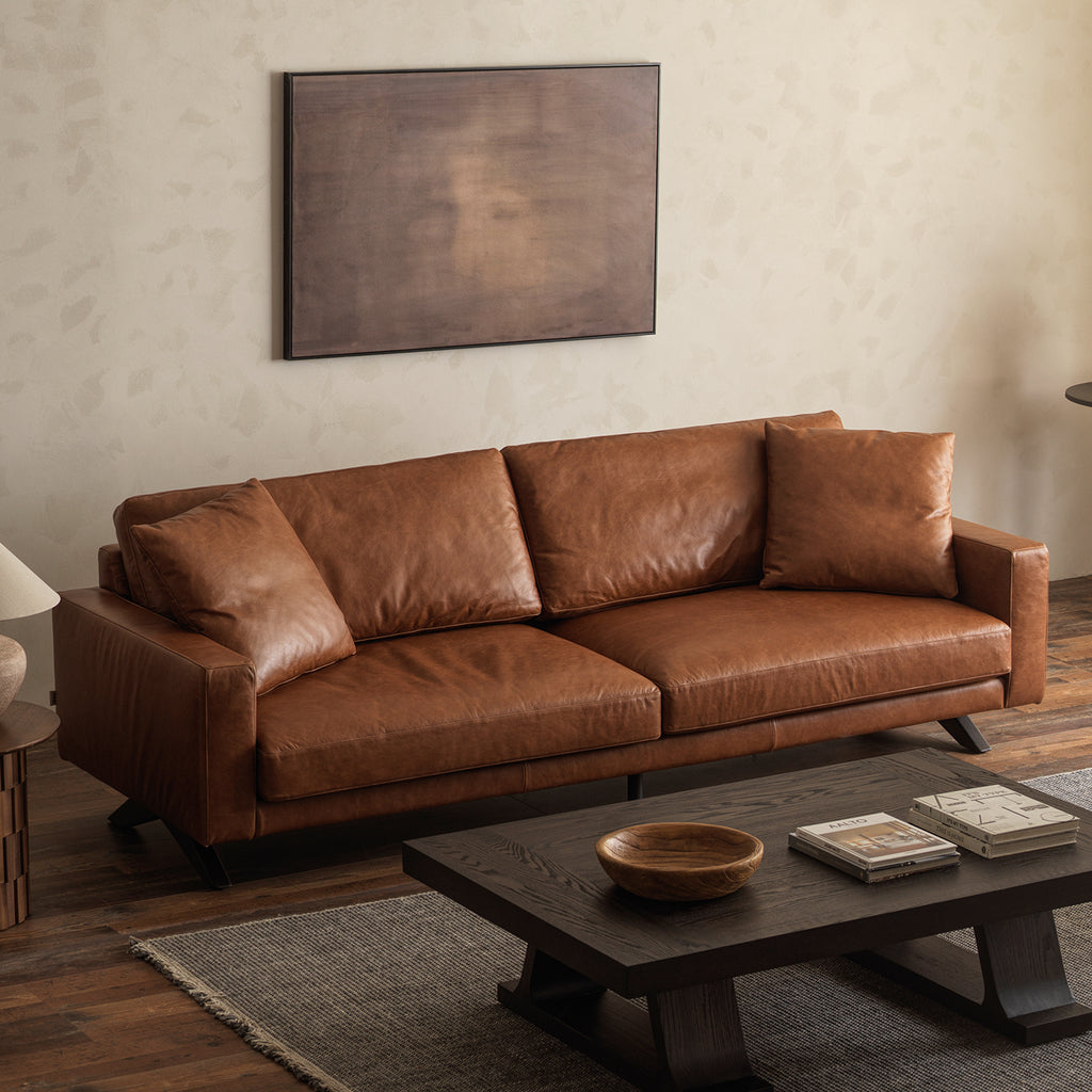 Elevated three-quarter view of 3-seater genuine leather sofa with accent throw pillows