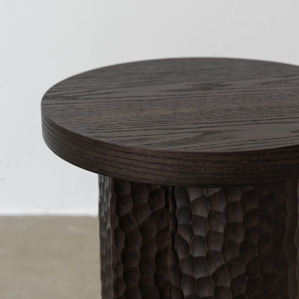 Close-up detail of round tabletop edge and hand-chiseled texture on red oak pedestal