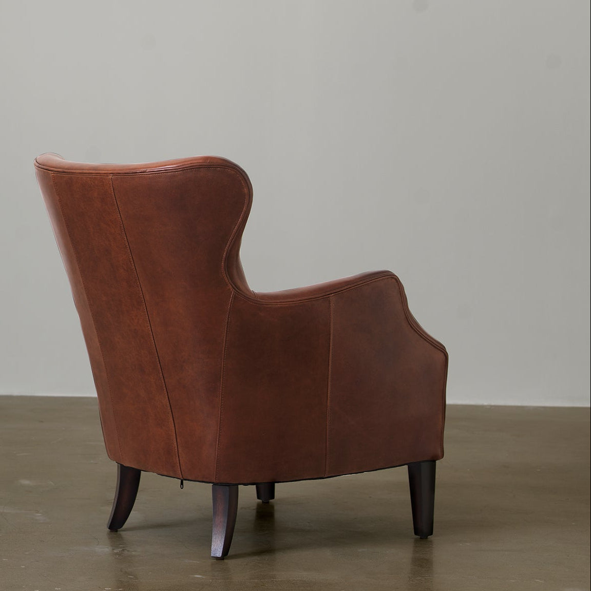 Cowhide leather wingback chair rear three-quarter view