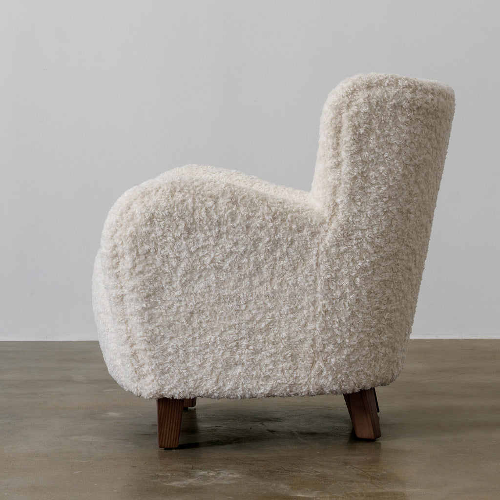 Side profile of Nuantuo cream textured wingback chair with a curved upholstered arm