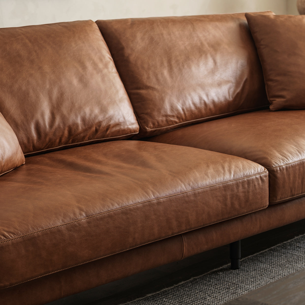 Close-up detail of genuine cowhide leather upholstery texture, natural grain, and tailored seam stitching