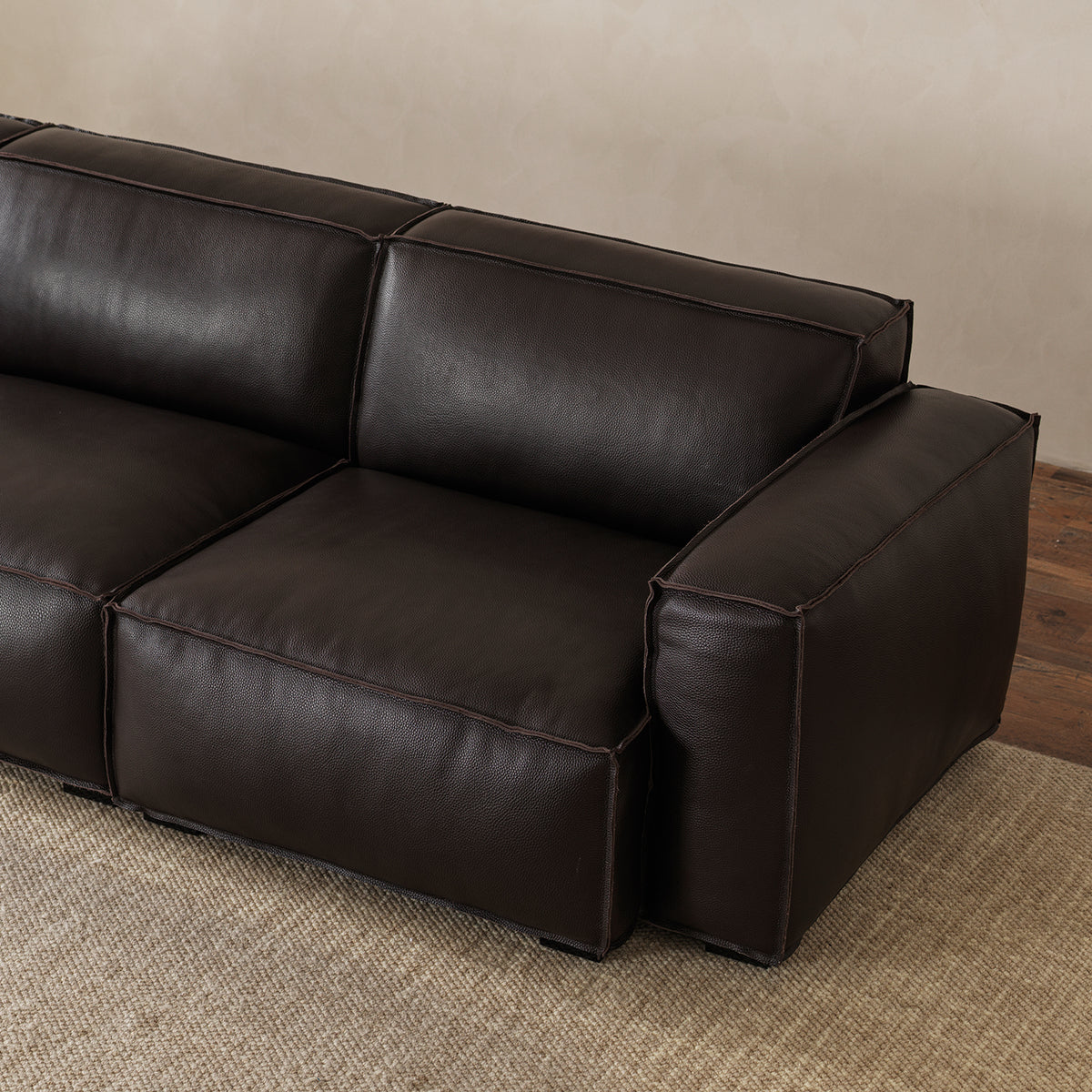 Close-up view of broad padded leather armrest and tailored edge piping detail