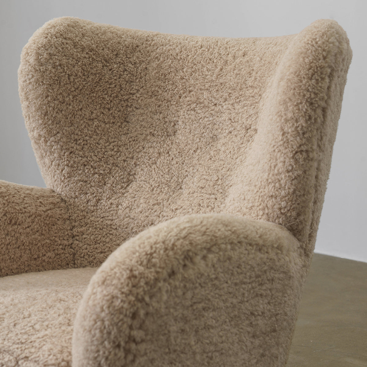 Close-up of Youran chair high wingback and rounded arm in beige textured fabric
