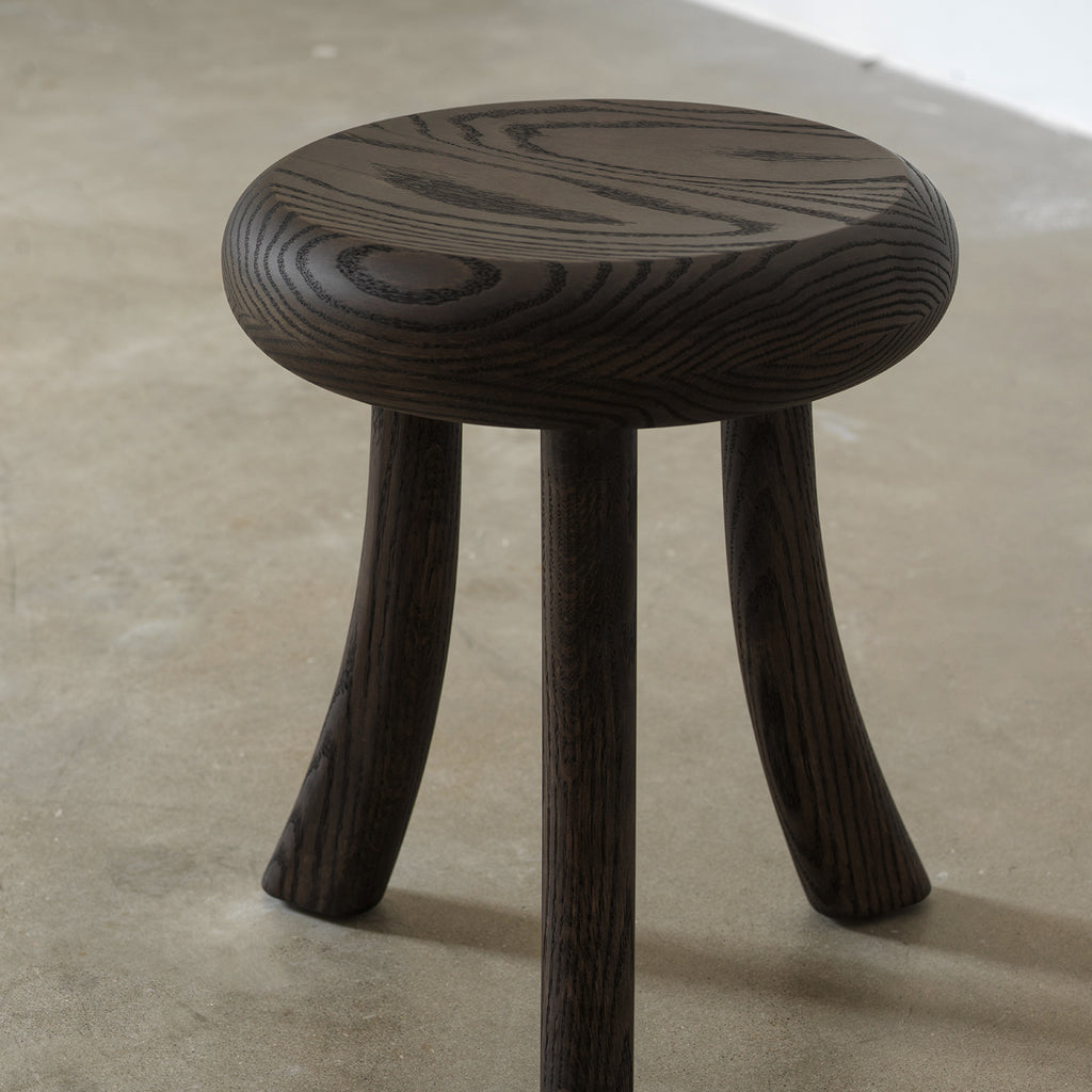 Three-quarter view of solid red oak 3-leg round side table with dark distressed wood finish