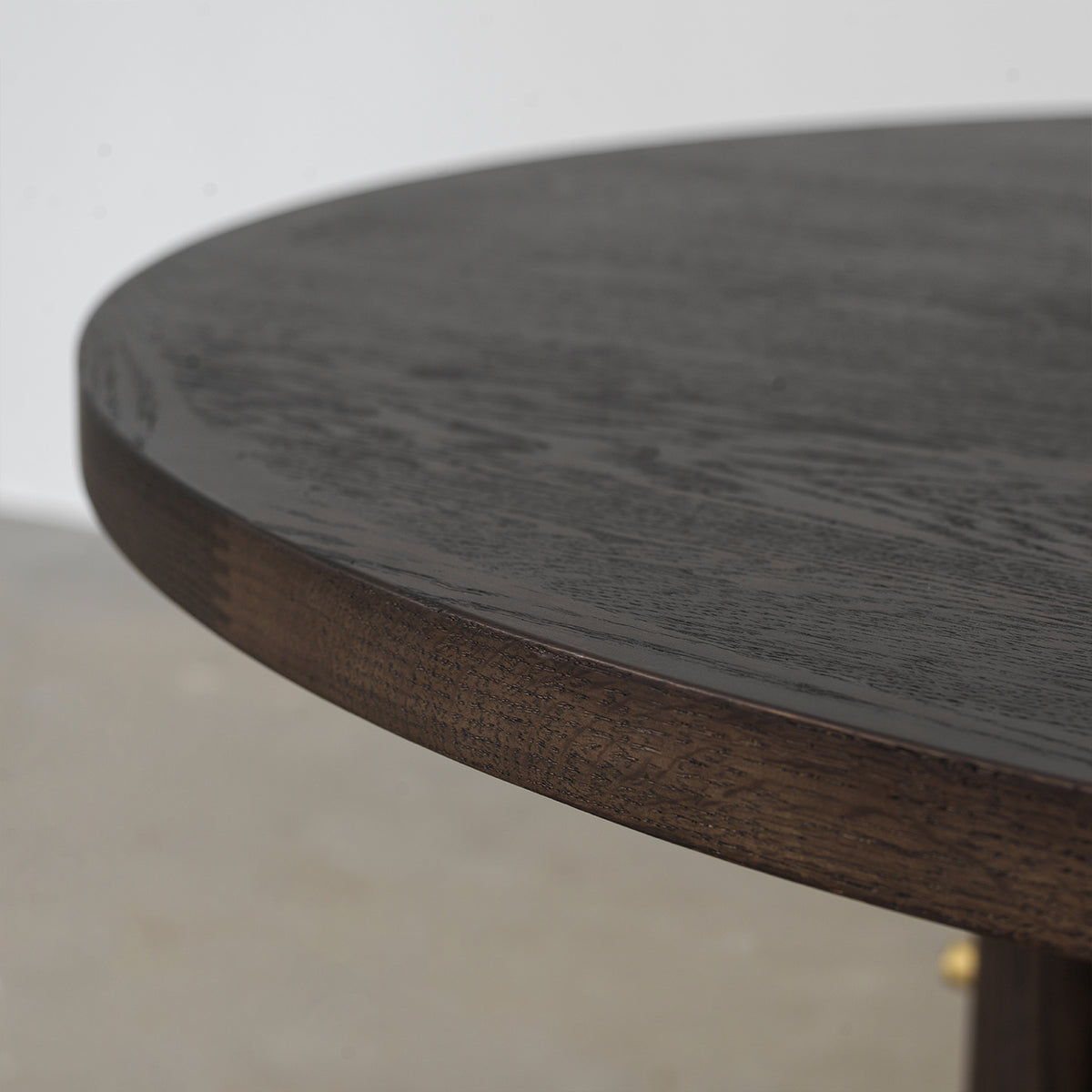 Curved circular tabletop edge showing natural wood grain texture and distressed dark finish, close-up material detail