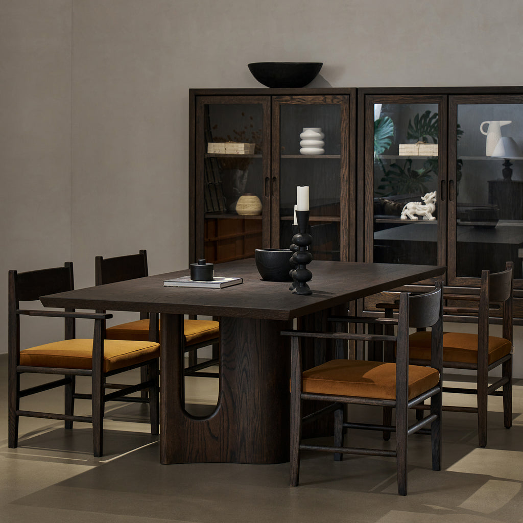 Three-quarter lifestyle setting of solid oak pedestal dining table with chairs and ceramic tableware