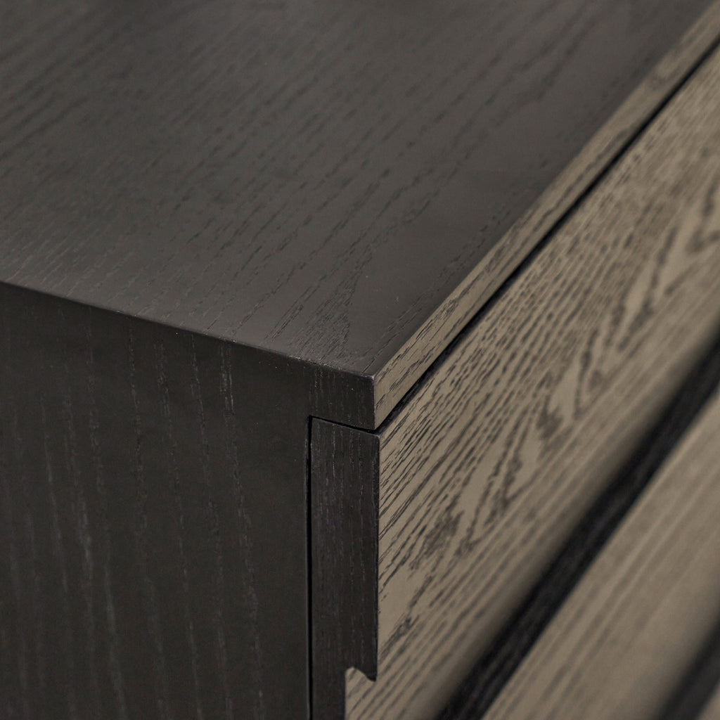 Corner detail of black oak sideboard showing seamless mitered edge and integrated concealed finger pull