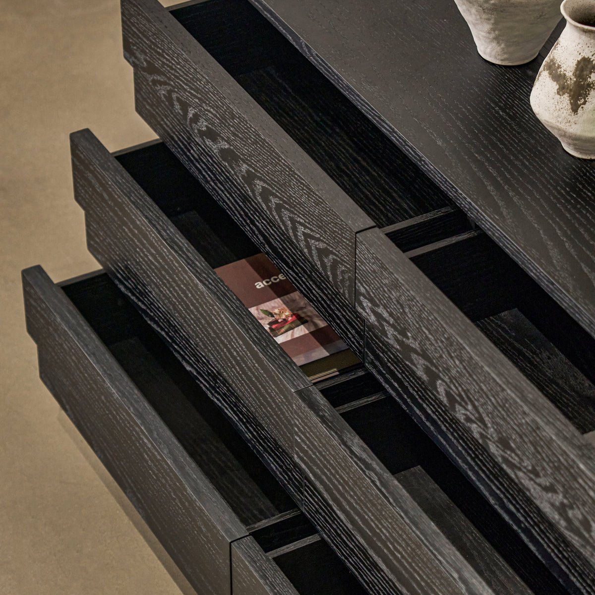 High-angle view of open drawers on black credenza showing organized interior storage capacity and smooth glides