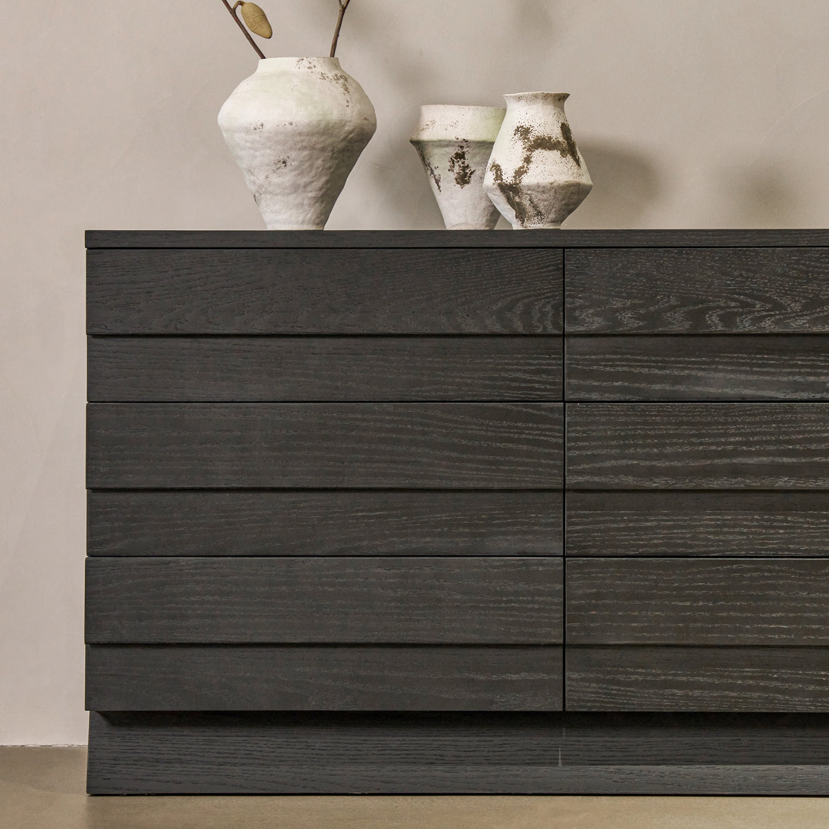 Close-up front view of black oak sideboard highlighting linear drawer divisions and natural wood grain texture