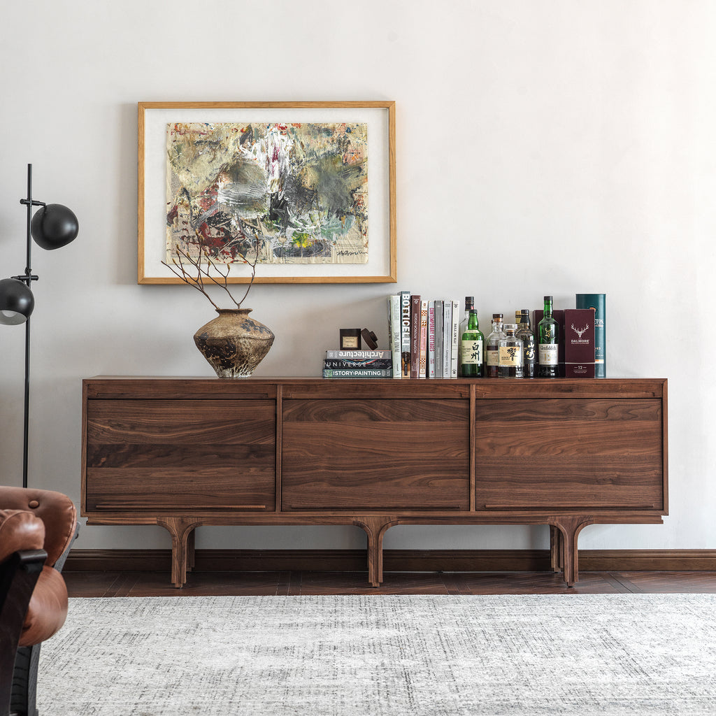  Extra-long black walnut sideboard in a living room with books and a ceramic vase on top