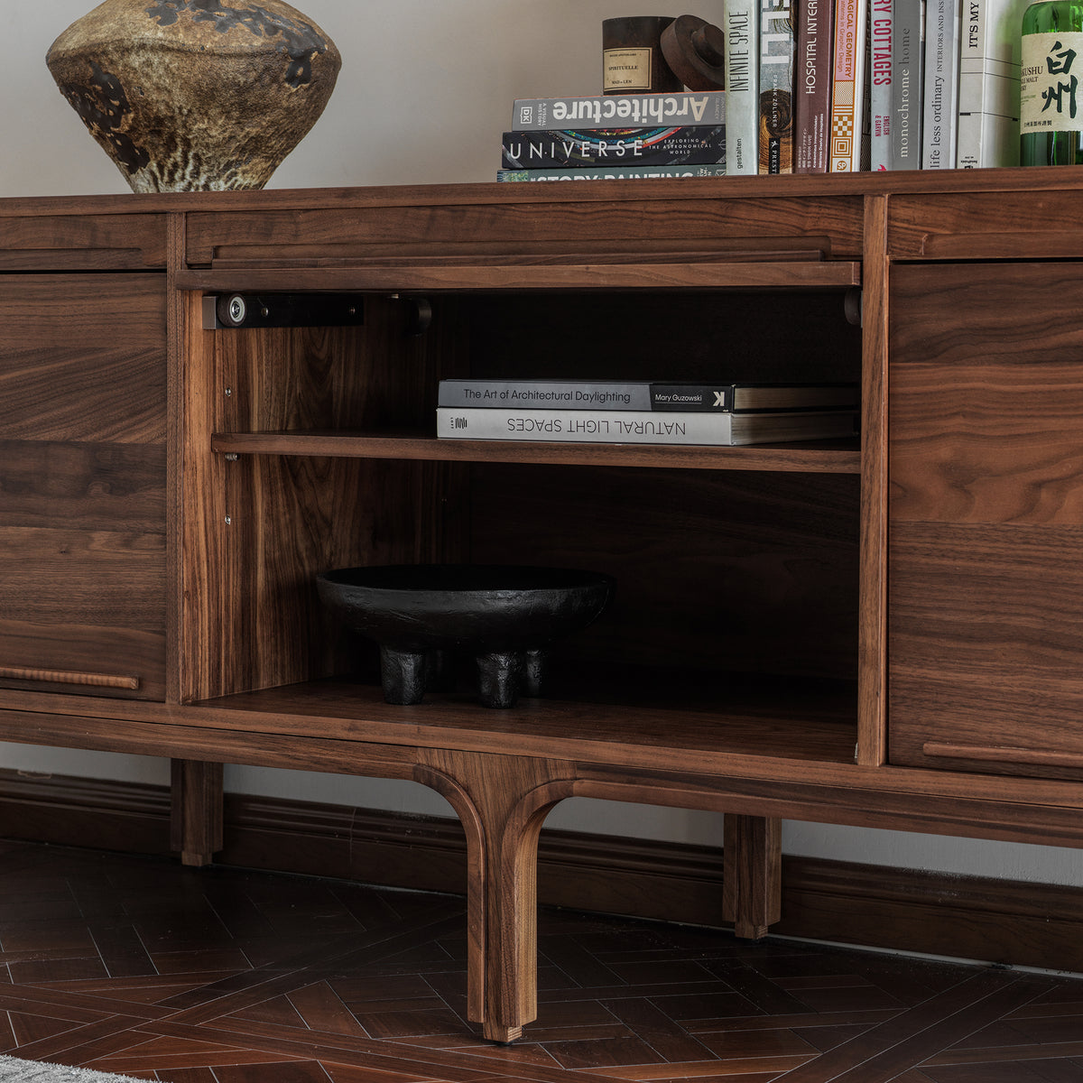  Open center door of a walnut sideboard revealing interior shelf storage