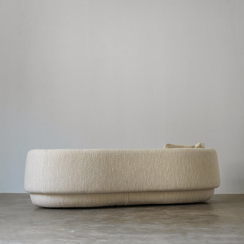Low-profile curved cream textured fabric sofa side view