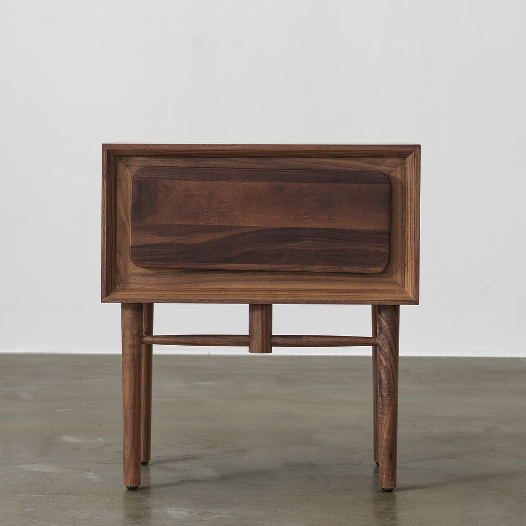 Front view of black walnut single-drawer nightstand with beveled frame and slender tapered legs