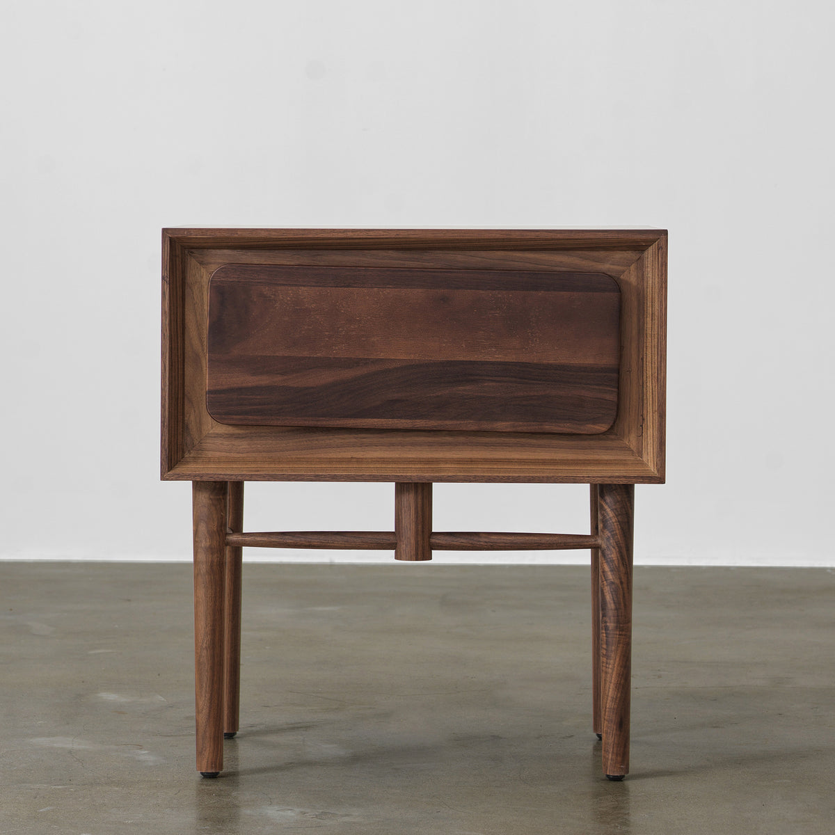 Front view of black walnut single-drawer nightstand with beveled frame and slender tapered legs