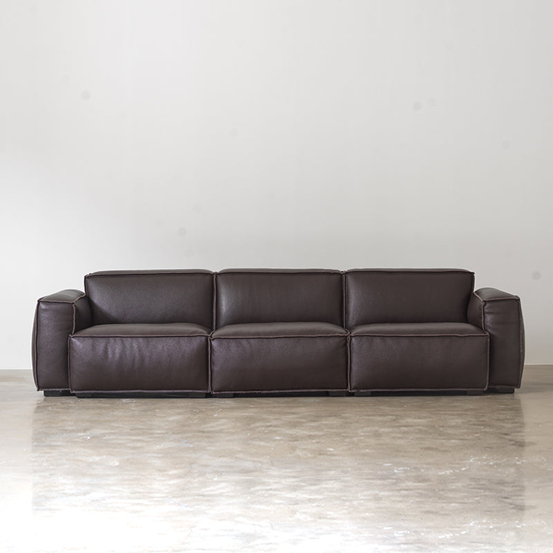 Front view of black low-profile genuine cowhide leather sofa with broad padded arms on white background